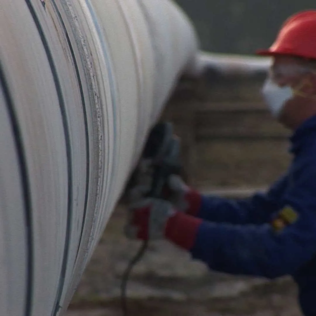 Technician finishing a glass-reinforced laminate on a pipe in the field