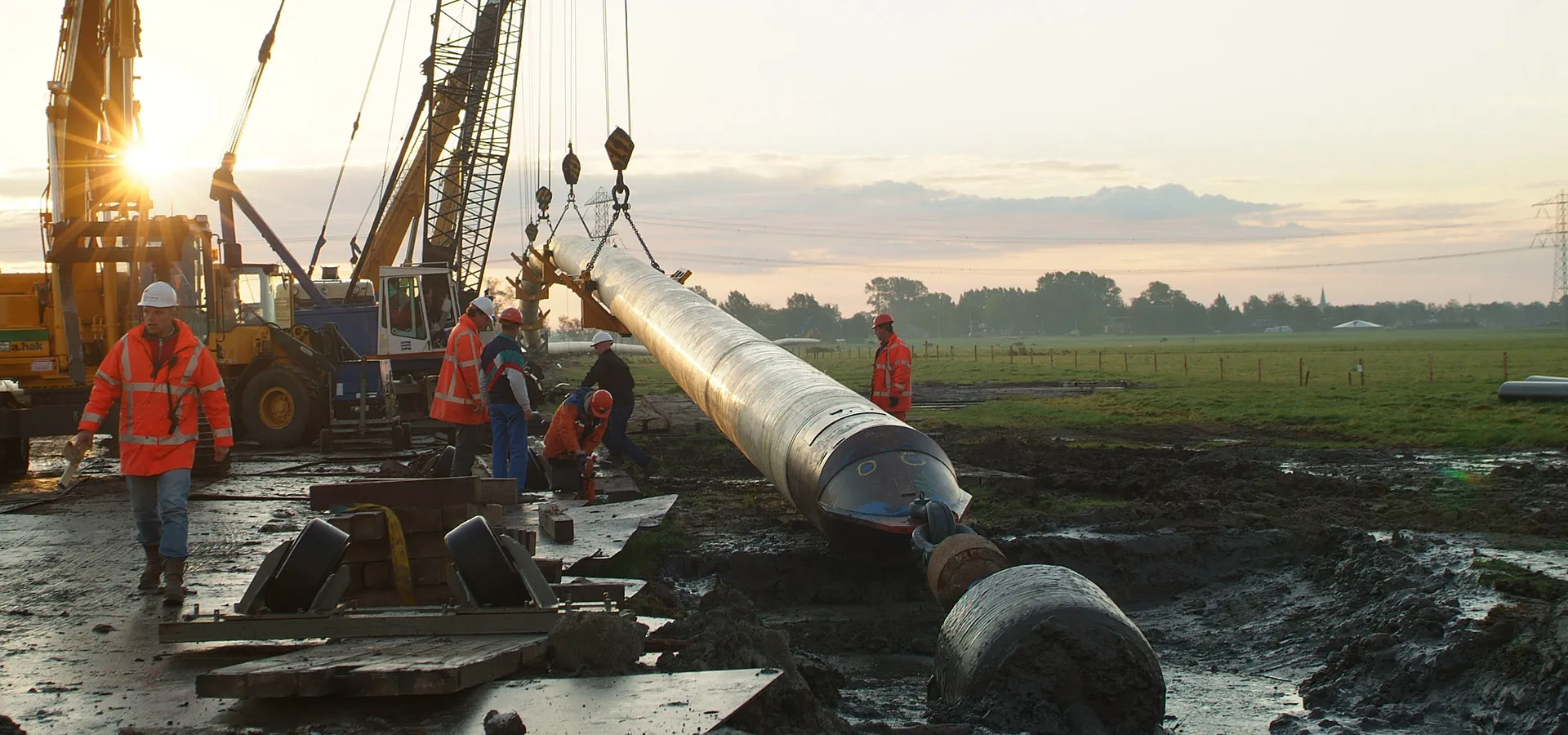 Crew guiding a coated pipe string into the ground at a horizontal directional drilling site