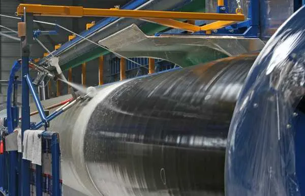 Close-up of the winding head applying a layer to a rotating pipe