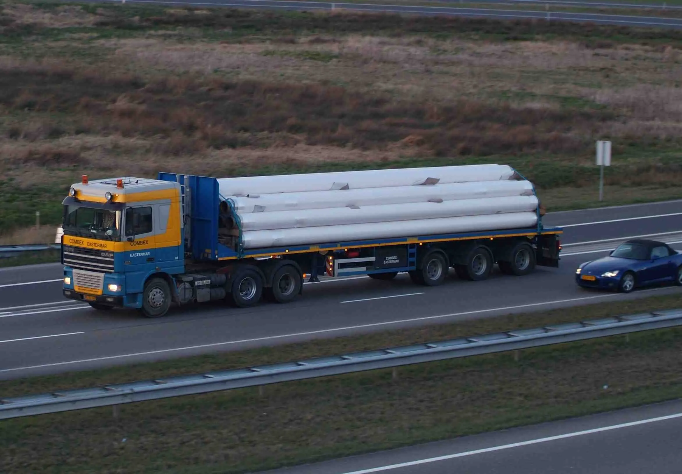 Truck carrying a load of coated pipes on the motorway