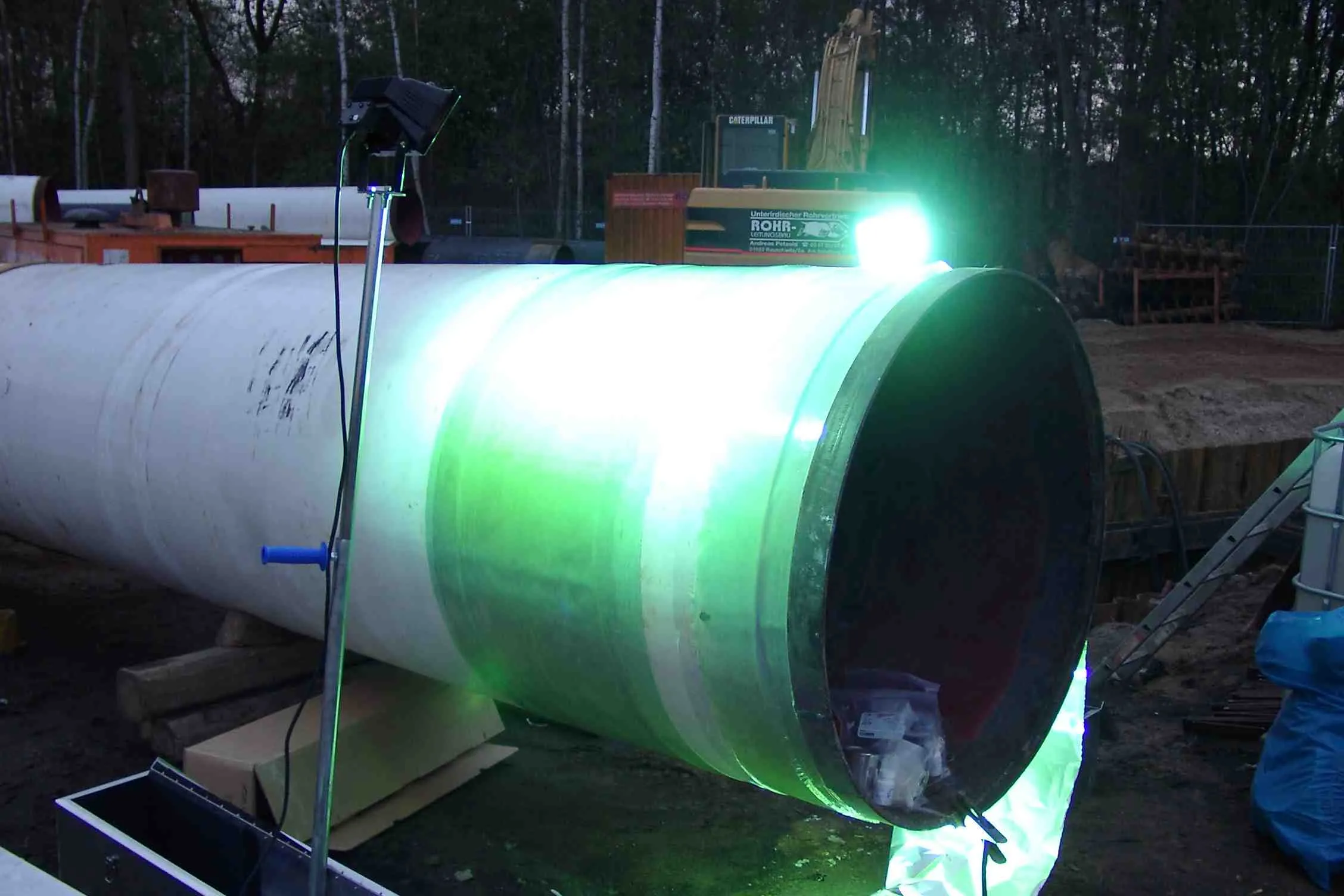 A laminate on a large pipe curing under UV light at a job site
