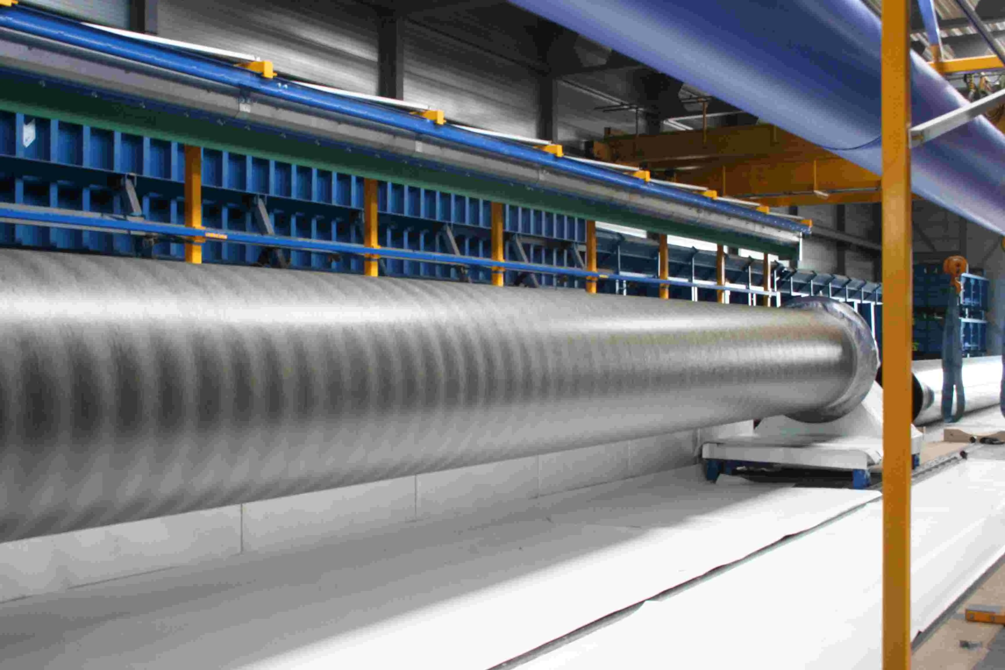 A long pipe rotating in the Blue Jetty spray-winding unit while a composite layer is applied